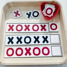 a tray filled with cut out letters on top of a white table next to a red heart