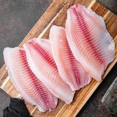 three raw fish fillets on a cutting board