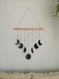 a wall hanging with five phases of the moon on it and a plant next to it