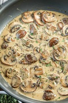 a pan filled with mushrooms and gravy on top of a table next to broccoli