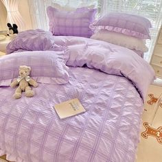 a bed with purple comforters and pillows on it