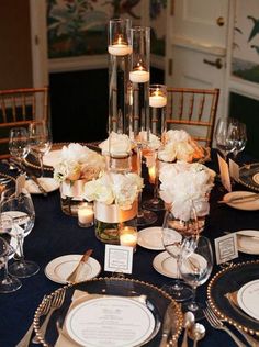 the table is set with candles, flowers and place settings for guests to sit at