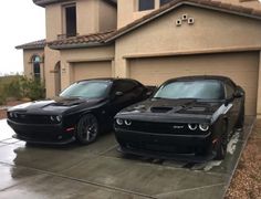 two black dodge vehicles parked in front of a house