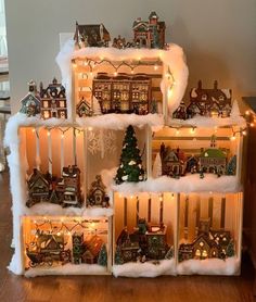 a group of christmas houses with lights and decorations on top of each other in front of a fireplace