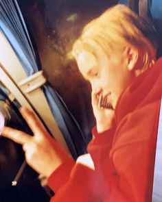 a man talking on a cell phone while sitting in a car next to a window