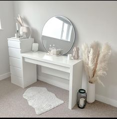 a white desk with a mirror, vase and other items on it in a room