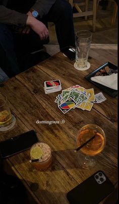 a wooden table topped with drinks and cards