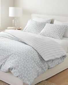 an image of a bed with white and blue comforter set on top of it