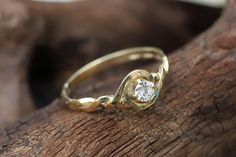 a gold ring with a diamond sitting on top of a piece of drifty wood