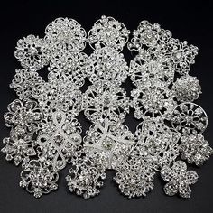 several pieces of silver and crystal broochies on a black surface with white background