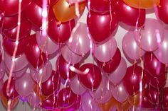 many red and pink balloons are hanging from the ceiling