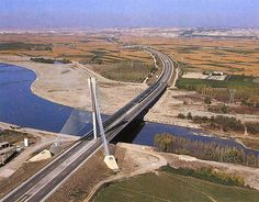 an aerial view of a bridge over a river and road in the middle of nowhere