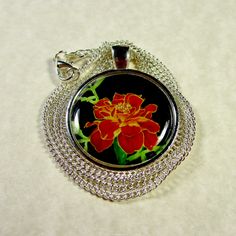 This marigold pendant features my watercolor painting depicting a orange and yellow flower against a black background in a 1-inch silver-tone setting. The original painting resides in my studio. The image is protected by an epoxy cabochon. Includes a 20-inch curb link chain with a lobster claw clasp. It was painted as October in a calendar of birth month flowers. My grandmother used to plant marigolds around the border of her vegetable garden to keep the rabbits out. My high school colors were o Orange Round Pendant Jewelry As Gift, Orange Round Pendant Jewelry Gift, Orange Round Pendant Jewelry For Gift, Orange Flower Pendant Jewelry Gift, Orange Flower Pendant Jewelry For Gift, Marigold Wedding, Pom Mom, Violet Wedding, Golden Retriever Mom