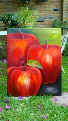 three red apples sitting on top of a green field