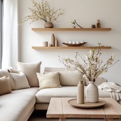 a living room filled with lots of furniture next to a wall mounted shelf full of vases