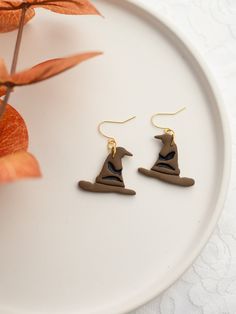 a pair of earrings sitting on top of a white plate next to a potted plant