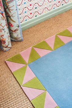 an area rug is on the floor in front of a wall with colorful patterns and designs