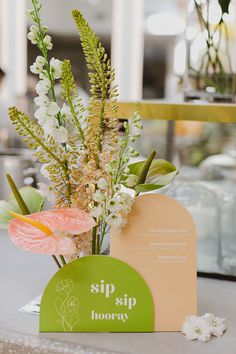 there is a vase with flowers in it and a sign that says sip hooray