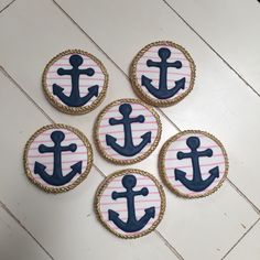 four decorated cookies sitting on top of a white table next to each other with an anchor