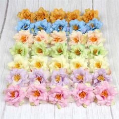 small multicolored flowers are arranged on a white wooden surface, ready to be used as hair clips