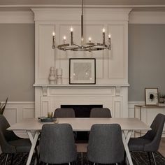 a dining room table with grey chairs and a fireplace in the backround area