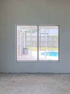 an empty room with two windows and a pool in the backround on one side