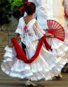 two people dressed in white and red dancing