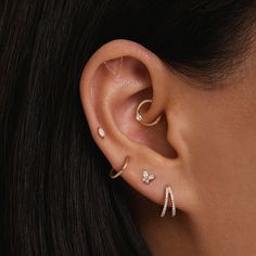 a woman wearing three different types of ear piercings