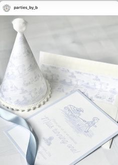 a white paper hat sitting on top of a table next to envelopes and ribbon