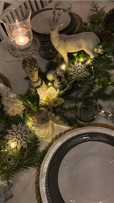 the table is set for christmas dinner with white plates and silver utensils on it