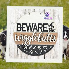 two dogs standing next to a sign that says beware of the wiggle butts