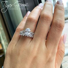 a woman's hand holding an engagement ring with three stones on top of it