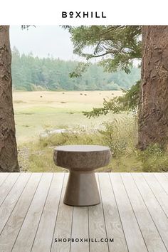 a bench sitting on top of a wooden floor in front of some trees and grass