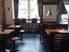 an empty restaurant with wooden tables and chairs in front of a window that looks out onto the street