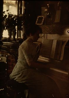 a woman sitting at a piano in front of an open book on top of a table