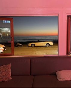 a couch sitting in front of a window next to a car parked on the beach