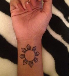 a woman's arm with a small sun tattoo on it