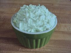 a green cup filled with whipped cream on top of a wooden table