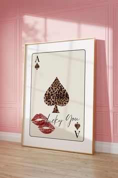 an ace card with lipstick on it in front of a pink wall and wooden floor