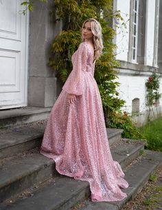 a woman standing on steps wearing a pink dress