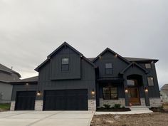 a gray house with two garages and lights on the front door is pictured in this image