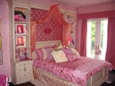 a bedroom decorated in pink and gold with a canopy bed, dressers, and window