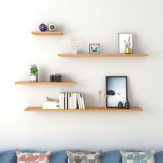 three wooden shelves on the wall above a blue couch with decorative pillows and other items