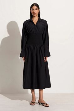 In luxe silk cotton, the Cervo Midi Dress is a midi shirt dress featuring a collared neck, button front bodice and long relaxed sleeves with flared cuffs. The drop waist is fully shirred for easy wear and gives way to an airy, gathered skirt that falls to a mid length. Rendered in black for timeless appeal, the Cervo offers easy one-piece summer shirting. Chic Midi Dress With Smocked Cuffs For Work, Midi Dress With Smocked Cuffs For Office, Midi Dress With Smocked Cuffs For Work, Elegant Midi Dress For Work With Smocked Cuffs, Chic Long Sleeve Midi Dress With Gathered Waist, Long-sleeved Dress With Smocked Cuffs For Work, Workwear Long Sleeve Midi Dress With Gathered Waist, Long Sleeve Midi Dress With Gathered Waist For Work, Chic Shirt Dress With Gathered Sleeves For Work