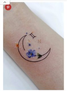 a small tattoo on the arm of a woman with flowers and stars around it's edges