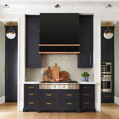 a kitchen with dark blue cabinets and white tile backsplash, wood flooring