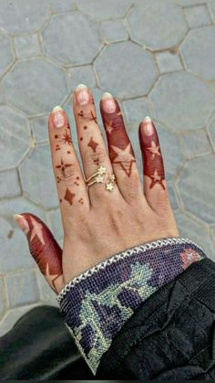 a woman's hand with red and white paint on it, showing her wedding ring