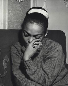 a black and white photo of a woman sitting on a couch with her hands to her face