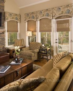 a living room filled with furniture and windows covered in roman shade shades on either side of the window