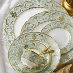 a set of four dinner plates with gold trimmings on the rim and sides